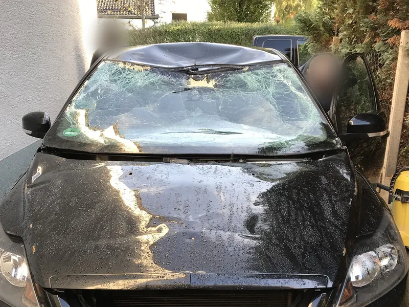 Auto mit zerstörter Windschutzscheibe bei der Schadensaufnahme